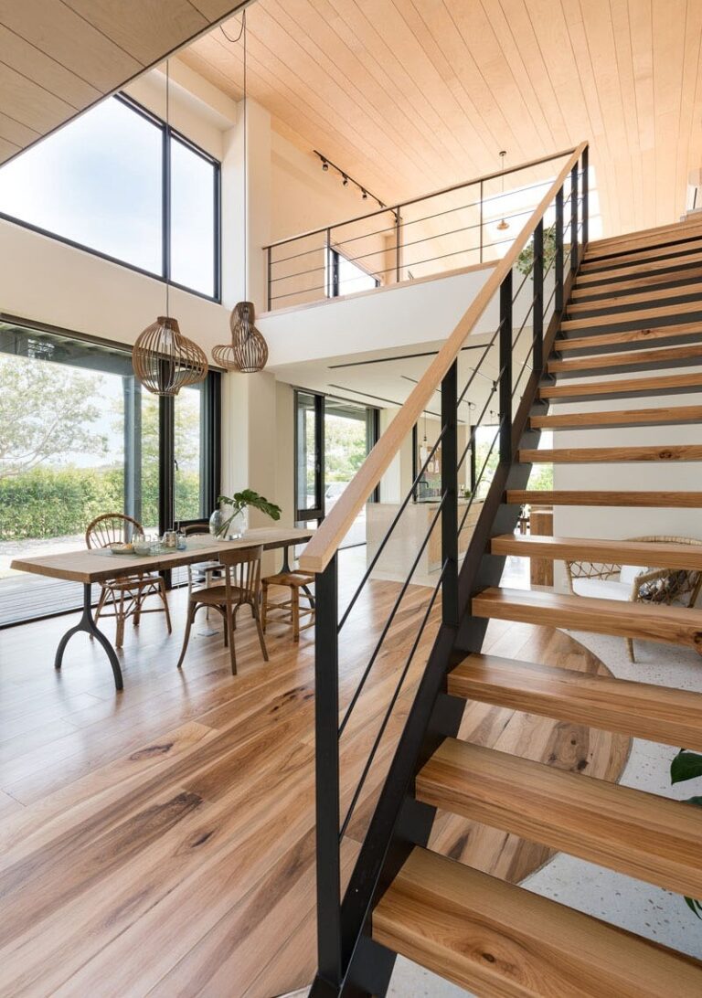Modern open-concept home interior in Bethesda featuring a light wood staircase and a stylish dining area with large windows.